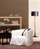 White armchair with cushion, side table, shelves and lamp in living room