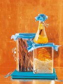 Chocolate cinnamon sticks, kumquat liqueur and orange sugar in glass jars