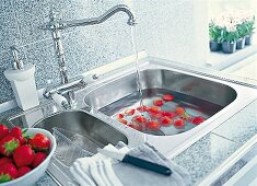 Erdbeeren werden gewaschen, Armatur in moderner Küche