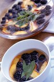 Close-up of peach with lemon verbena and blackberries in bowl