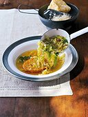 Savoy cabbage soup with zuppa alla canavesana being served with bowl of parmesan cheese