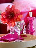 Close-up of glass with red flower on tray and lit candle on side