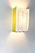 Illuminated paper lamp hanging on white wall