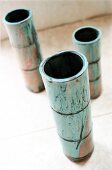 Close-up of three green bamboo shaped flower vases on floor