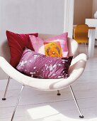 White floorings and white chair with red, purple and pink pillows in living room