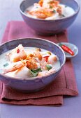 Coconut soup with shrimp, carrots, sprouts, cod and coriander in bowl