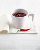 weiße Tasse mit Chili-Mousse au Chocolat, daneben eine Chili-Schote