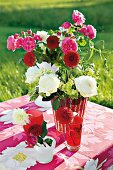 Strauß mit Rosen und Dahlien in Vase auf Tisch im Garten, Sommer