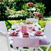 Table with bottle of milk, strawberries and mug in garden