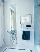 Ein weißes Badezimmer mit langem, schmalem Spiegel hinter Waschbecken