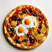 Pizza topped with black olives and fried eggs on white background
