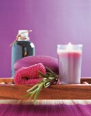 Close-up of purple spa soap, lit glass candle and rosemary leaves