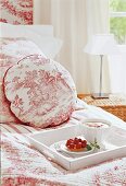 Breakfast tray on bed sheet and cushion with red motif in bedroom