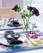 gedeckter Tisch, Blumen als Deko lila, weiß, mit bunten Tischsets