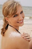 Portrait of cheerful blonde woman with salt crystals on shoulder wearing bikini, smiling