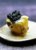 A new potato with caviar on an old-fashioned plate