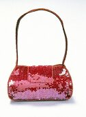 Close-up of red and pink sequined handbag on white background