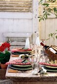 A Mediterranean themed table outside laid with wine and olives