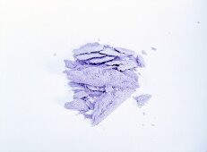 Close-up of crushed purple eye shadow on white background