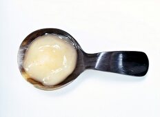 Close-up of orange flavoured dollop face mask in horn spoon on white background