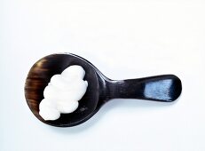 Dab of white face mask in horn spoon on white background