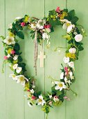 Flower arrangement in the shape of a heart made of spring flowers, with a cross