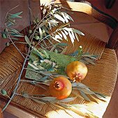 2 Granatäpfel liegen auf einem Foto auf einem Stuhl, Olivenzweige