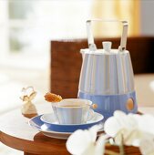 Blue striped teapot and cup with rocky candy on wooden table