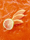 Close-up of papayas, limes and orange puree sauce