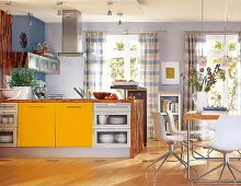 Küche in Gelb und Blau, Elemente aus Glas u. Holz, Riesenkochblock mittig