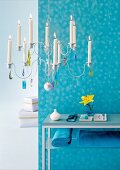 Blue side table with towels and lit candlestick hanging in front of blue wall
