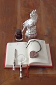 Magnifying glass, letter openers and heart pendant on diary with inkwell