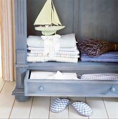 Linen, a decorative ship and a bundle of lavender in a purple wooden dresser