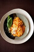Pumpkin risotto with basil leaves and walnuts in plate, overhead view