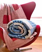 Patchwork blanket rolled and spread out on red chair