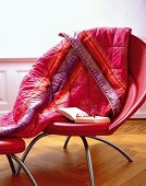 Book, spectacles and pink quilt with ornamental pattern on armchair