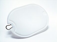 Plastic chopping board in oval shape with metal handle on white background