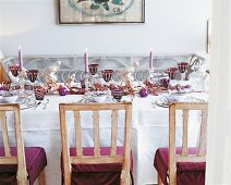 Dining table with purple chairs decorated with Christmas decorations and white table cloth