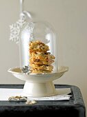 Stack of figs and nut biscuits on fruit stand covered with glass on table