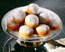 Stack of plum donuts with icing sugar on glass plate