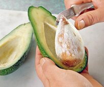 Close-up of seed being removed from avocado with a knife