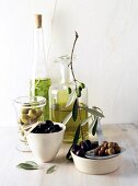 verschiedene Oliven und Olivenöl in Flaschen und Schalen