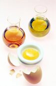 Close-up of two bottles of olive oil, apple cider vinegar and bowl of egg york