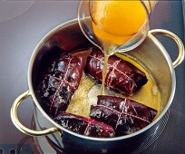 Beef wrapped in red cabbage leaves cooked in pot with broth