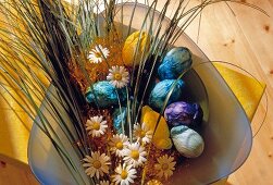 Easter eggs wrapped in tissue paper with flowers in bowl