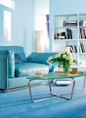 blauer Ledersessel in blauem Zimmer Bücherregal, Glastisch, Blumenvase