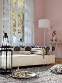 Living room with sofa, day bed and large iron lantern in front of pink wall