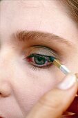 Beautiful woman applying eyeliner with eye pencil, close-up