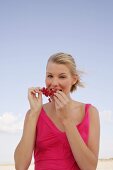 Blonde woman holding a branch of red currants in hand, smiling