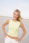 Portrait of pretty woman with windswept hair wearing yellow top standing and smiling